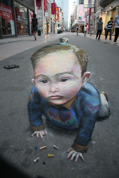 3D illusion of a toddler crawling in the street