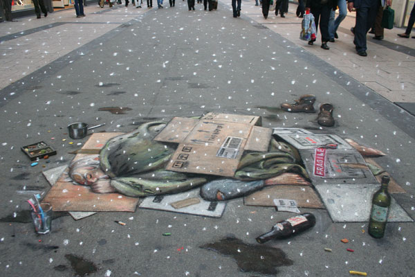 3D street drawing of a homeless man sleeping on cardboard with the snow starting to fall