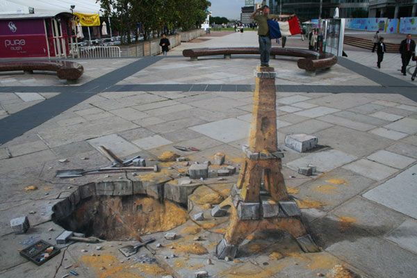 3D illusion of the Eiffel Tower made out of sand, leaving a hole next to it where the sand and stones were supposedly taken from.