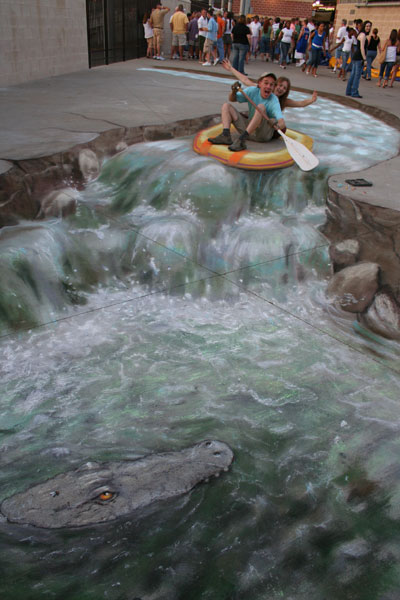 3D sidewalk drawing of an inflattable boat and a river with 2 real people navigating the rapids